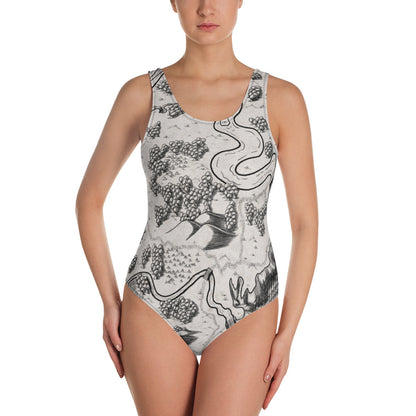 A model wears the Humble Beginnings map one piece swimsuit by Deven Rue.