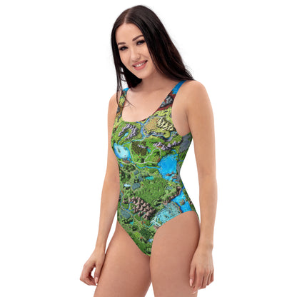 A model wears the Taur'Syldor map one piece swimsuit by Deven Rue, left side view.