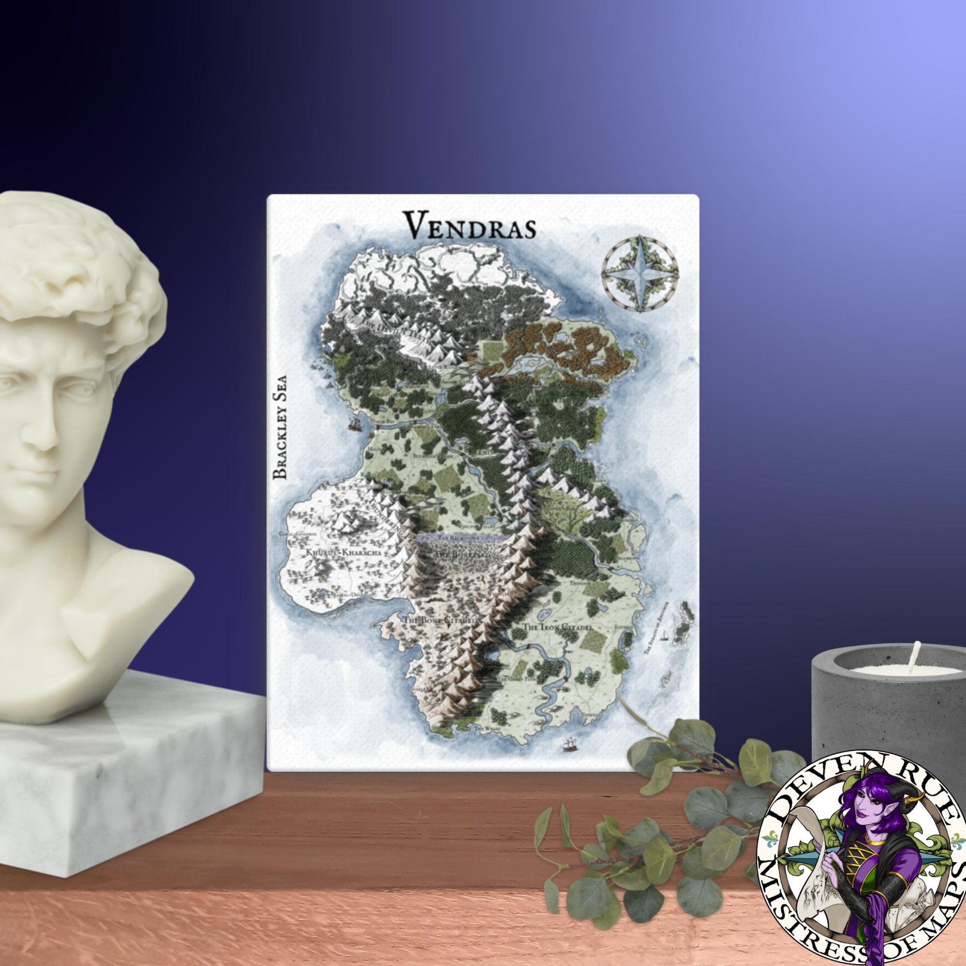 A 12" by 16" canvas print of the Vendras map by Deven Rue sits on a shelf with a stone bust, candle, and greenery.