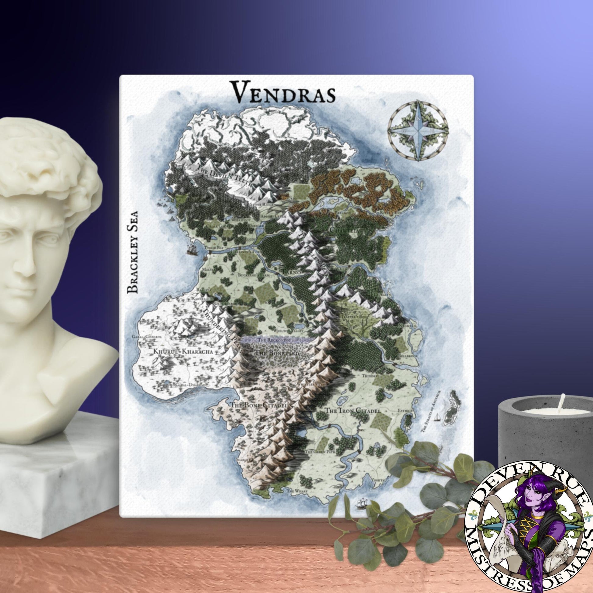 A 16" by 20" canvas print of the Vendras map by Deven Rue sits on a shelf with a stone bust, candle, and greenery.