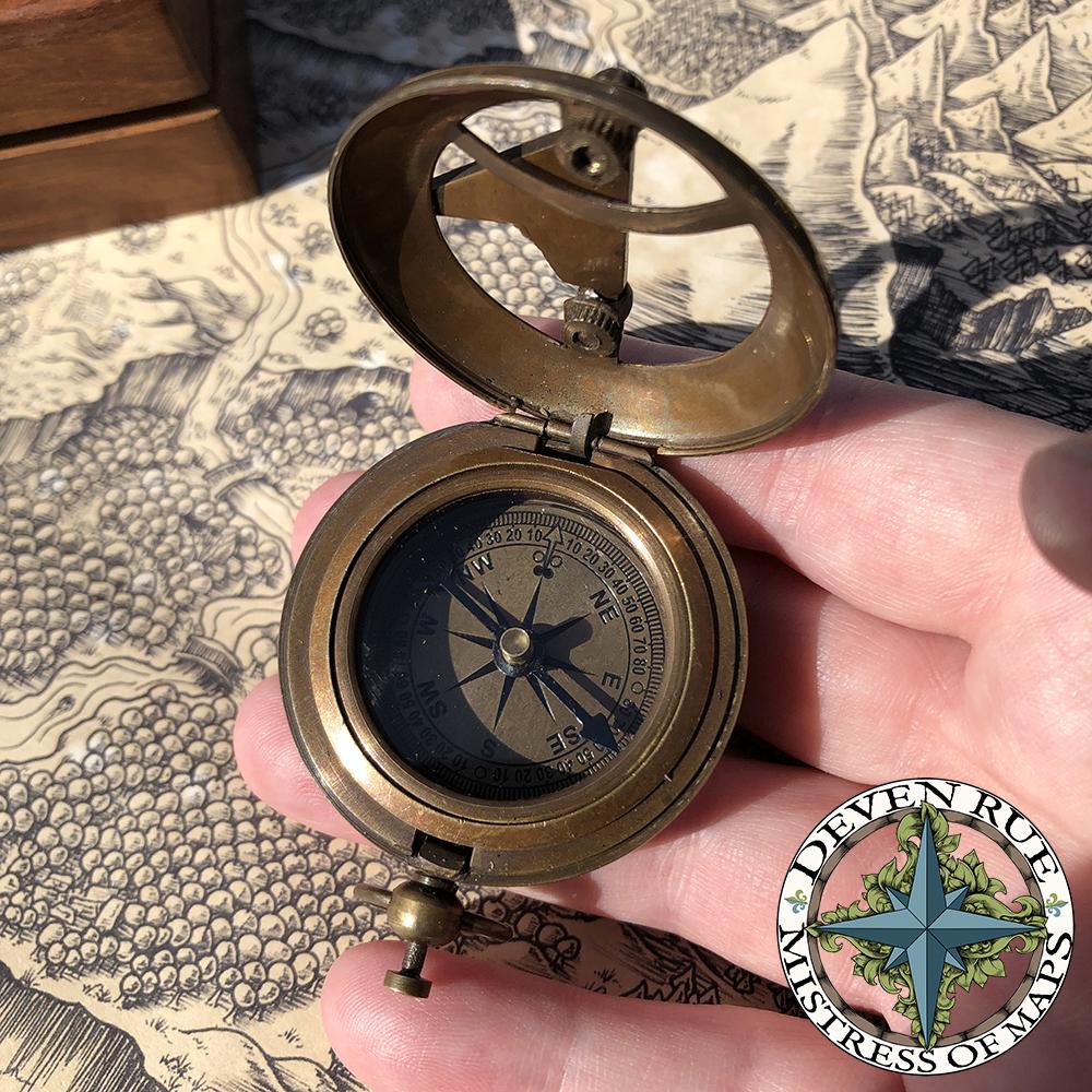 A hand holds the pocket compass open over a map.