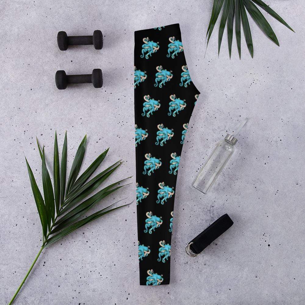 The Tangled Octopus leggings by Deven Rue are folded in half surrounded by exercise accessories.