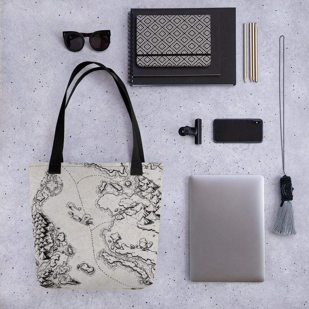 A tote bag with a black and tan map by Deven Rue surrounded by sunglasses, books, a phone, laptop, and other accessories for scale.