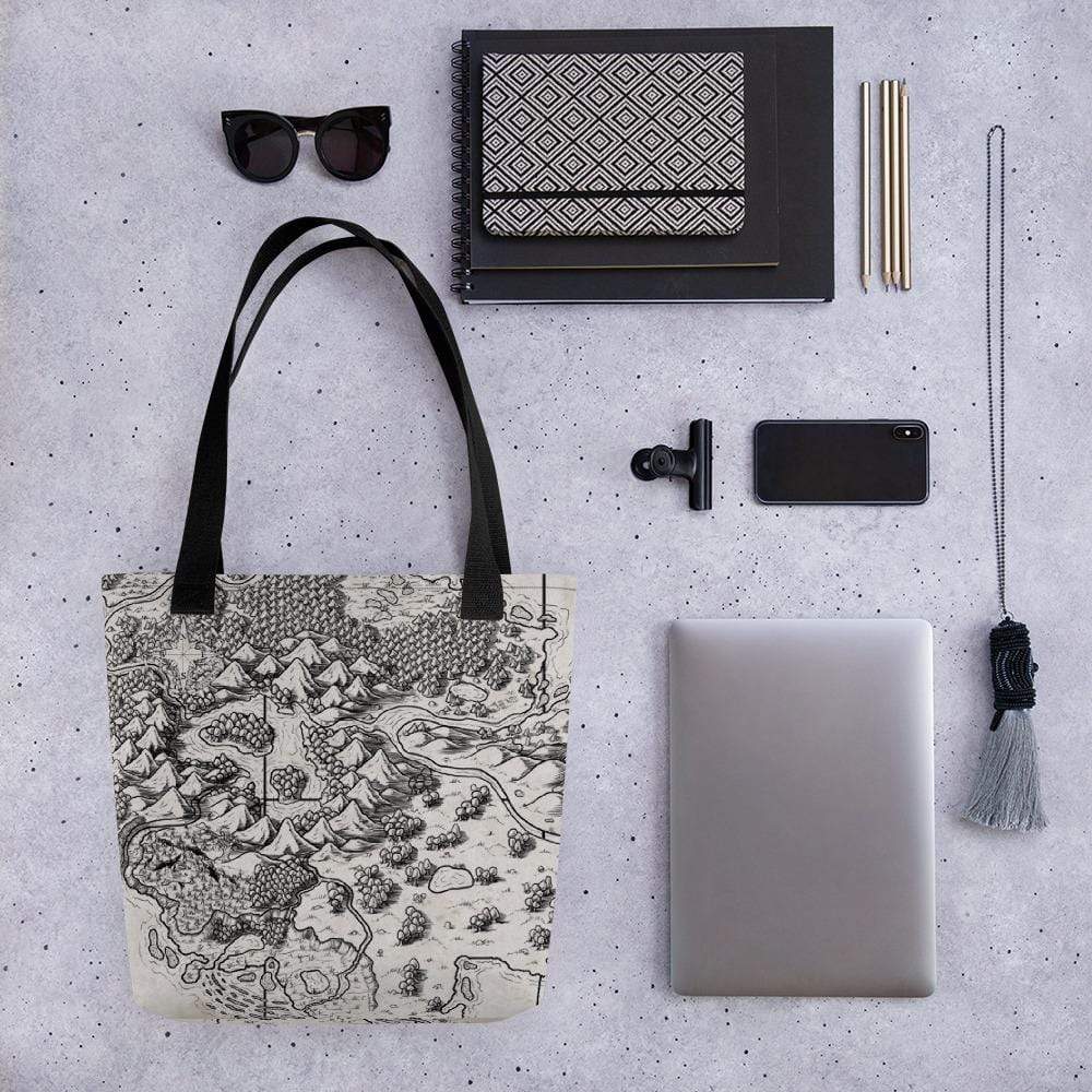 A tote bag with a black and tan map by Deven Rue surrounded by sunglasses, books, a phone, laptop, and other accessories for scale.
