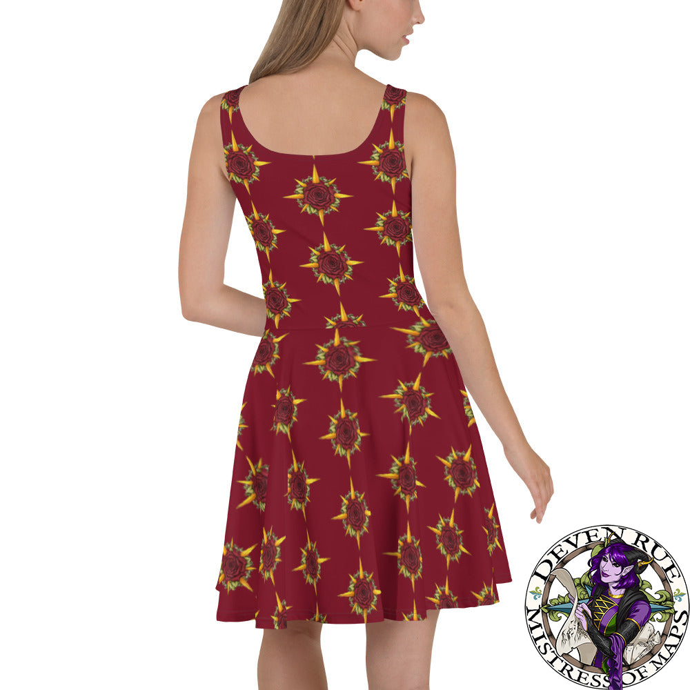 A model wears a skater skirt tank dress in burgundy with the Druid Compass Rose ibn a pattern all over it, back view.