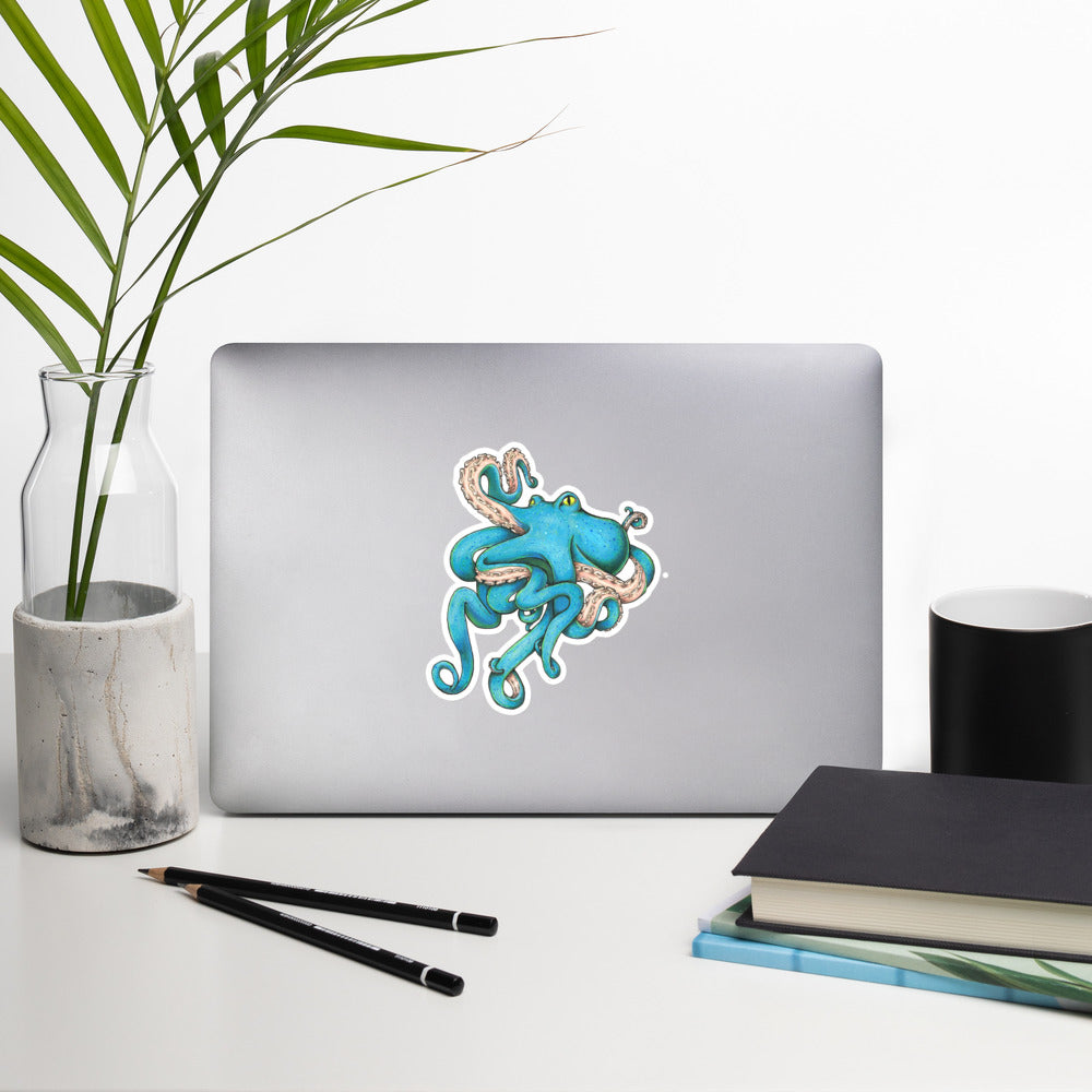 The 5.5" blue Tangled Octopus illustration sticker stuck to a laptop on a generic looking desk.