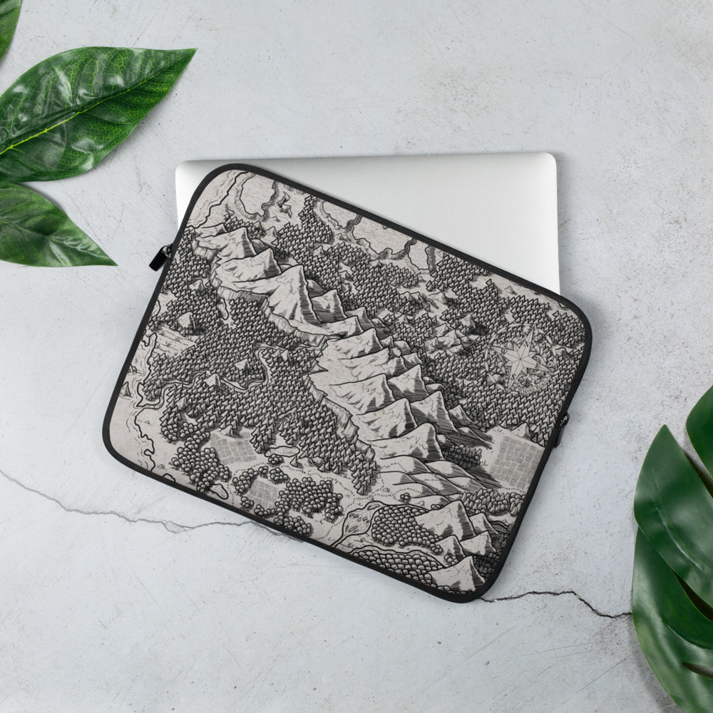A laptop sleeve with a black and white map of a forest mountain range. Greenery is around for scale.