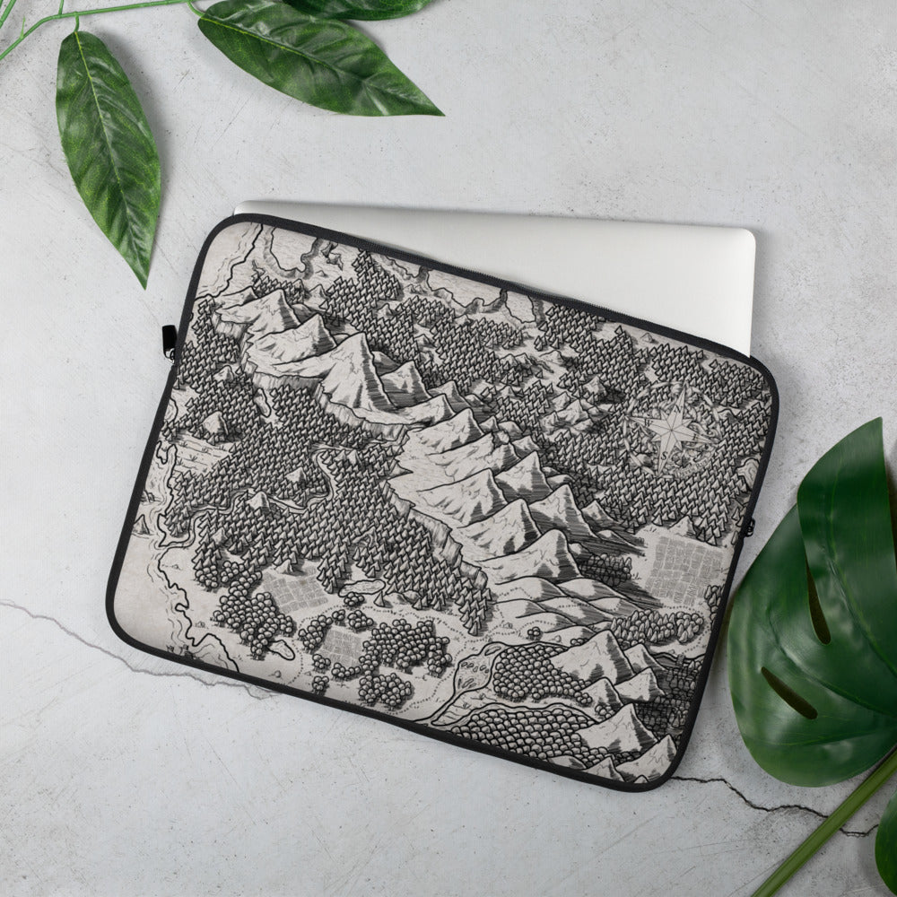 A laptop sleeve with a black and white map of a forest mountain range. Greenery is around for scale.