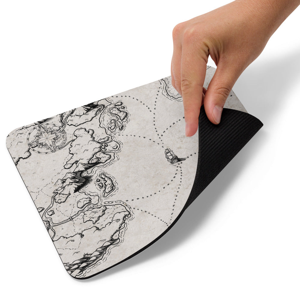 A hand lifts up the corner of the Sailing into the Unknown map mousepad.