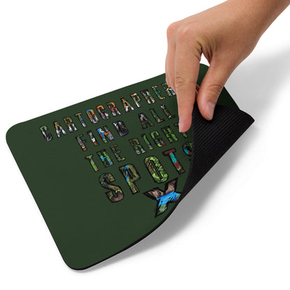 A hand picks up the corner of the "Cartographers find all the right spots" mousepad.