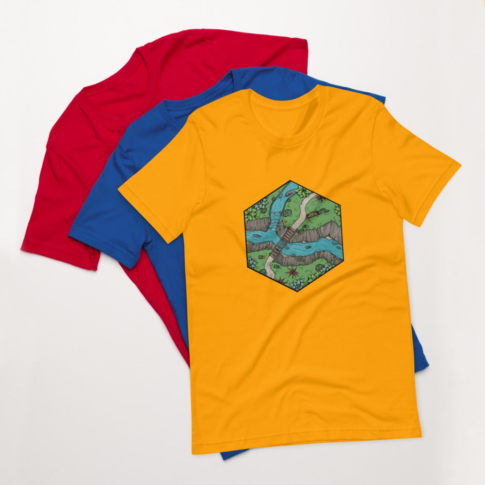 A gold version of the Perilous Crossing shirt sits on top of the royal blue and bright red shirts.