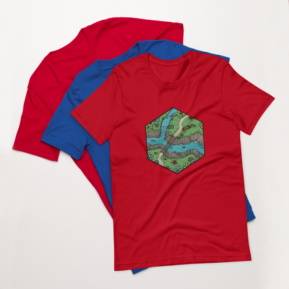 A red version of the Perilous Crossing t-shirt sits on top of a blue and another red version.